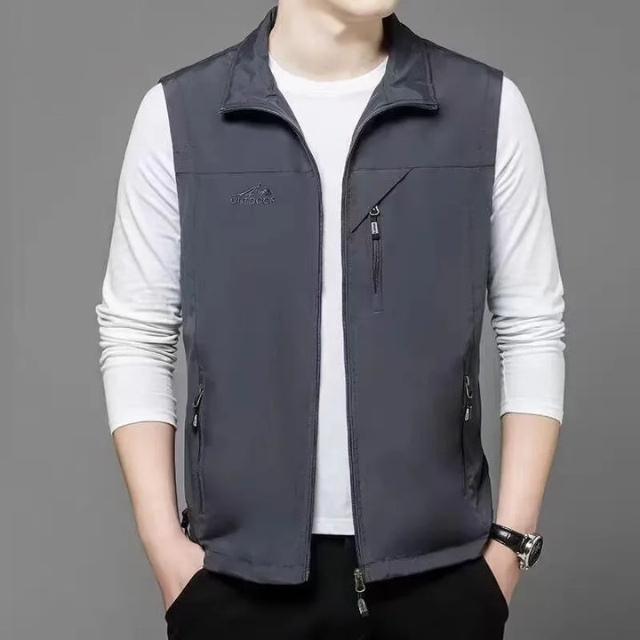 Graue Outdoor-Weste für Herren über weißem Langarmshirt, Reißverschlusstaschen, lässiger Stil, ideal für Herbstmode und Freizeitkleidung.