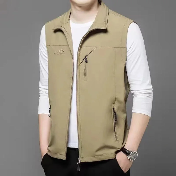 Beige Herrenweste über weißem Langarmshirt, Reißverschlusstaschen, lässiger Stil, ideal für Outdoor-Aktivitäten, modisches Herrenoutfit.