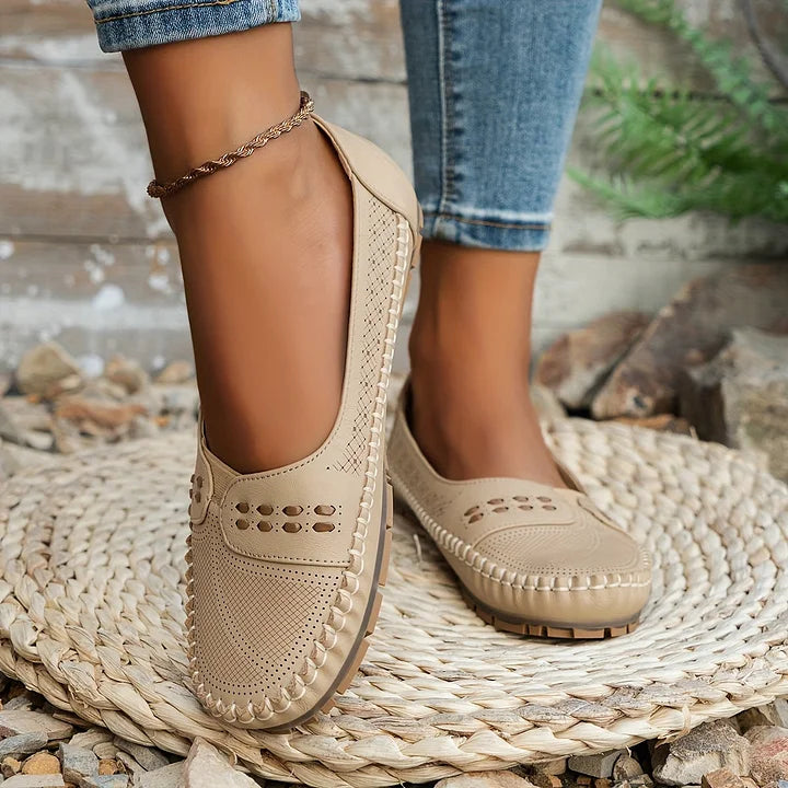 Beige Mokassins aus Leder für Damen, getragen mit blauen Jeans, auf einem geflochtenen Teppich. Bequeme, stilvolle Schuhe für den Alltag.