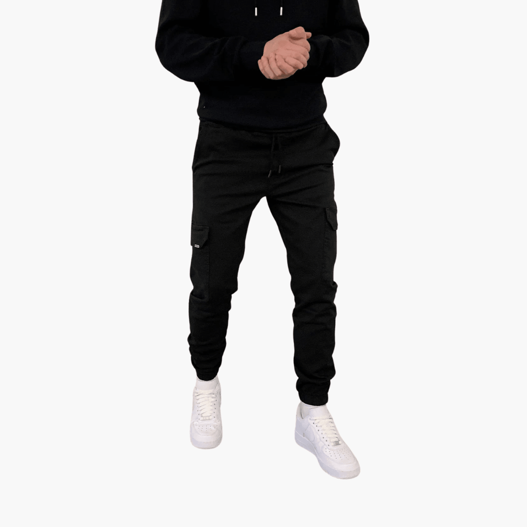 Schwarze Cargo-Jogginghose für Herren, kombiniert mit weißen Sneakers und schwarzem Hoodie. Bequeme Freizeitmode, ideal für den urbanen Look.