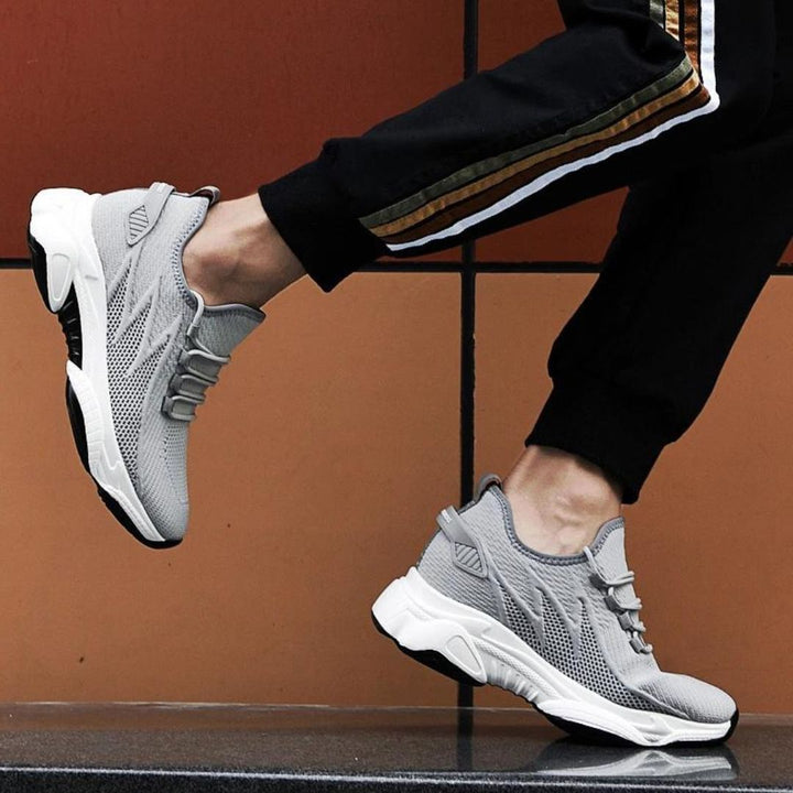 Graue Sportschuhe beim Laufen, moderne Sneaker mit atmungsaktivem Mesh-Obermaterial, schwarze Jogginghose mit Streifen, sportlicher Lifestyle.