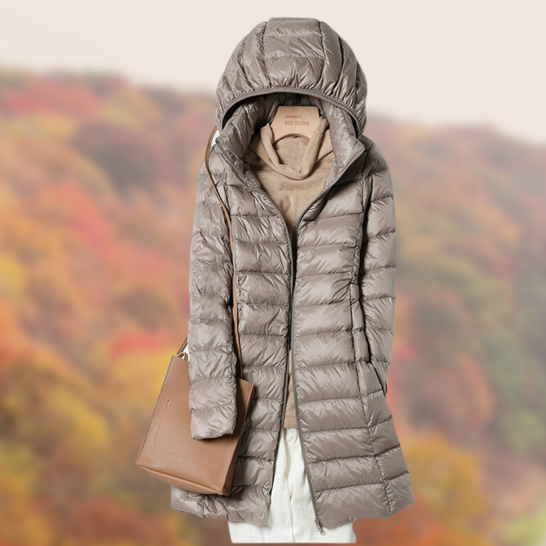 Damen-Daunenmantel in Beige mit Kapuze, kombiniert mit brauner Handtasche, vor herbstlichem Hintergrund. Ideal für Herbstmode und Outdoor-Aktivitäten.