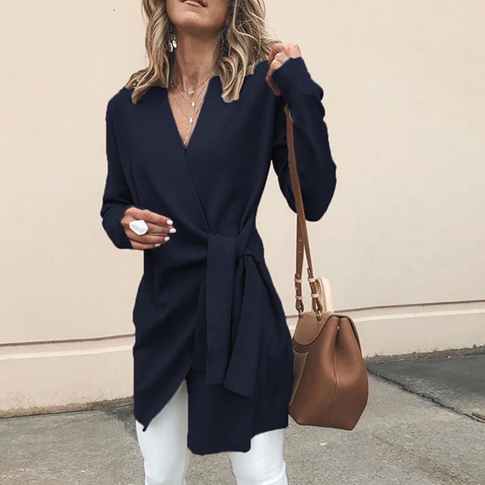 Frau in dunkelblauer Wickelbluse, weiße Hose, braune Handtasche, modisch, lässig, Herbstmode, Streetstyle, elegantes Outfit.