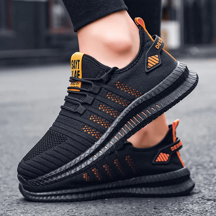 Schwarze Sportschuhe mit orangefarbenen Akzenten, atmungsaktivem Mesh-Obermaterial und rutschfester Sohle, ideal für Laufen und Fitness.