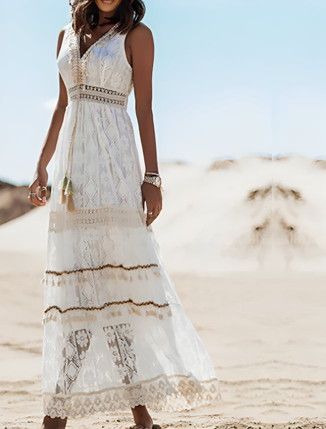 Frau in weißem, ärmellosem Spitzenkleid mit Boho-Muster steht in Wüstenlandschaft; Sommermode, elegantes Maxikleid, Strandkleidung.
