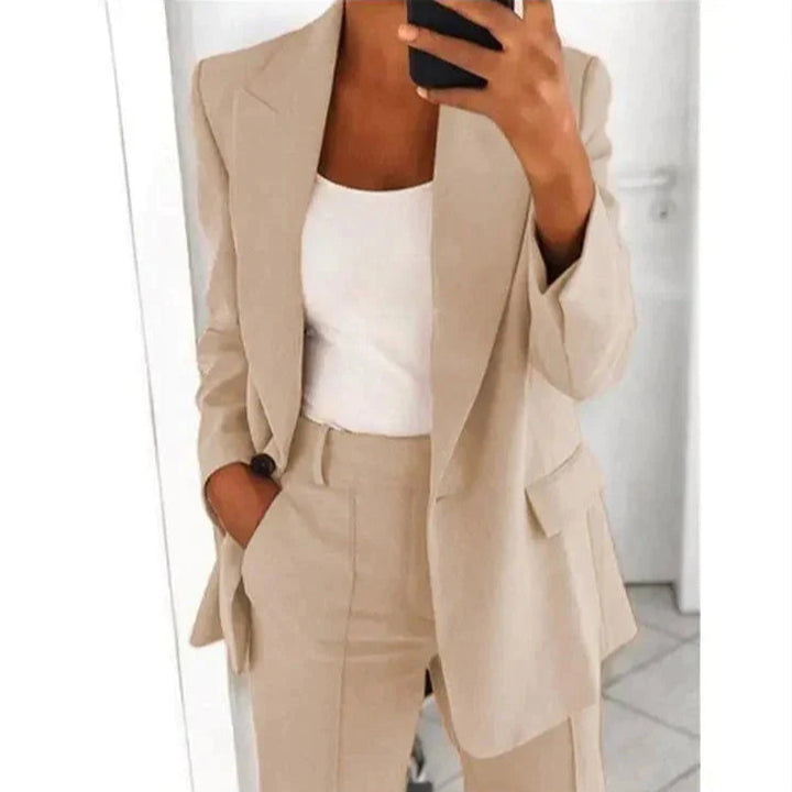 Eleganter Damenanzug in Beige, bestehend aus Blazer und Hose, kombiniert mit weißem Top. Businessmode, stilvoll, modern, Bürooutfit.