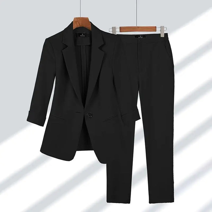 Schwarzer Damenanzug mit Blazer und Hose auf Kleiderbügeln, elegantes Business-Outfit, klassische Mode, formelle Damenbekleidung.