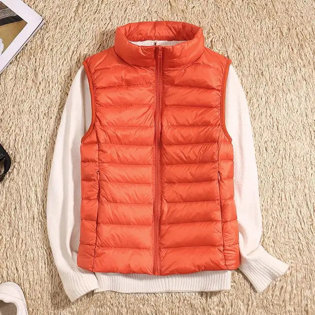 Orangefarbene Steppweste auf cremefarbenem Pullover, flach auf beigem Teppich liegend. Modische Herbstbekleidung, warm und stilvoll.