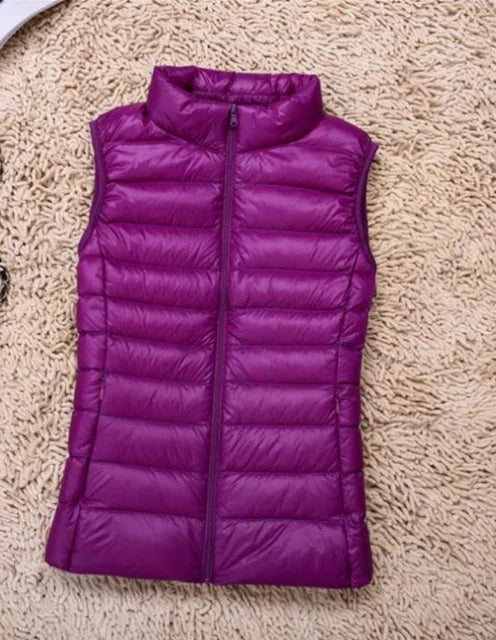 Lila Daunenweste auf beigem Teppich, ärmellos mit Stehkragen und Reißverschluss. Modische Damenbekleidung, ideal für Herbst und Winter.