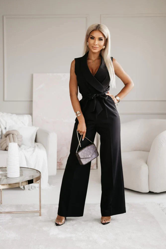 Frau in elegantem schwarzen Jumpsuit posiert in modernem Wohnzimmer, hält eine Designer-Handtasche. Stilvolle Mode, luxuriöse Inneneinrichtung.