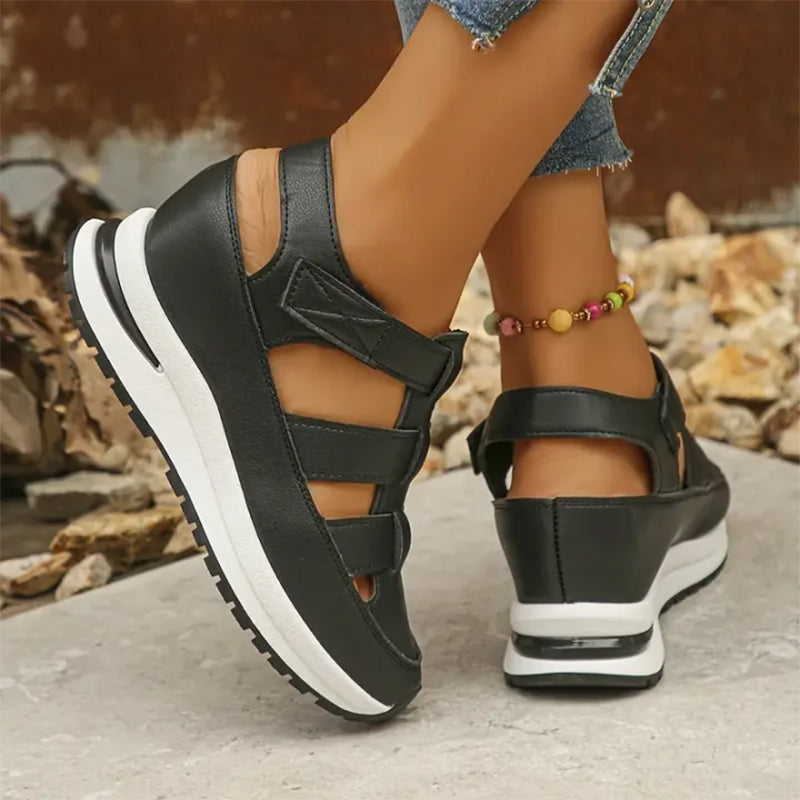 Schwarze Damen-Sandalen mit Keilabsatz, sportlich und bequem, kombiniert mit Jeans und buntem Fußkettchen, ideal für Sommermode und Freizeit.