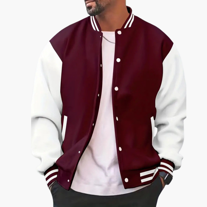 Mann in modischer College-Jacke in Bordeaux und Weiß, lässig mit weißem T-Shirt und Kette. Trendige Herrenmode, sportlicher Look.