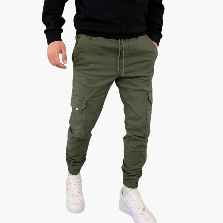 Grüne Cargo-Jogginghose für Herren mit Taschen, kombiniert mit weißen Sneakers. Bequeme Freizeitmode, ideal für sportlichen und lässigen Stil.
