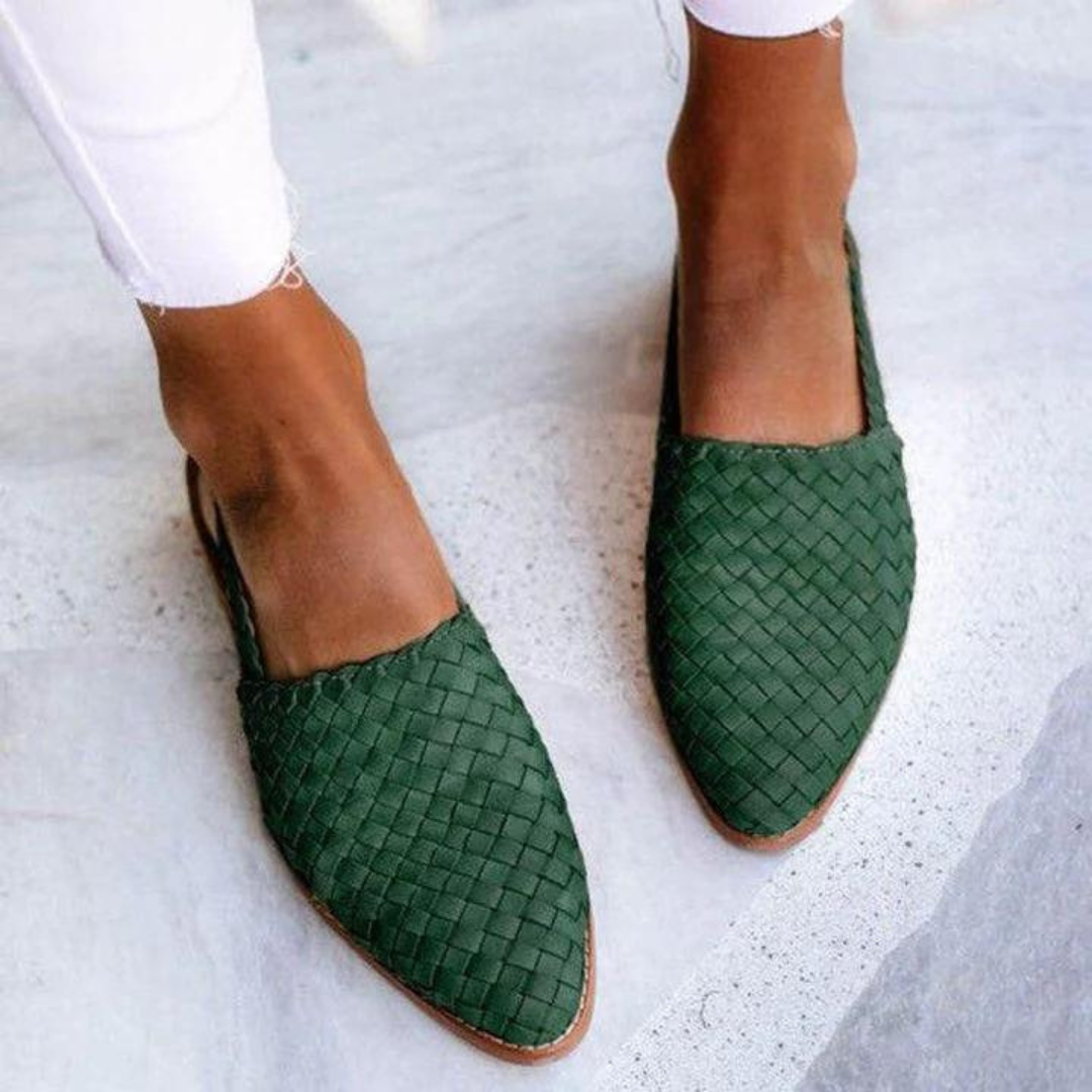 Grüne geflochtene Damen-Slipper auf weißem Hintergrund, getragen mit weißen Jeans. Modische, bequeme Sommerschuhe für Damen.