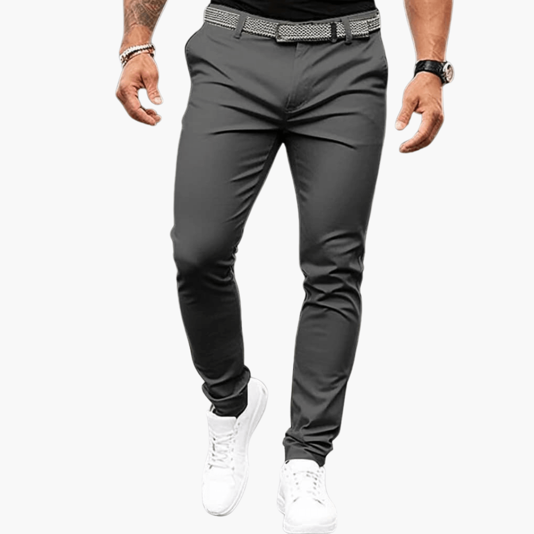 Herrenmode: Elegante graue Chinohose, schmal geschnitten, kombiniert mit weißem Gürtel und weißen Sneakers. Ideal für Business und Freizeit.