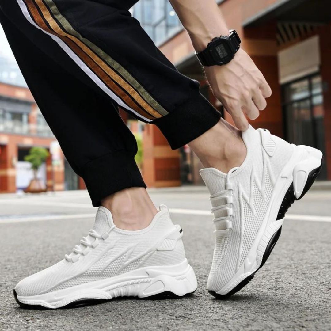 Weiße Sportschuhe für Herren auf urbanem Hintergrund, getragen mit schwarzer Hose mit Streifen. Moderne Sneaker, ideal für Laufen und Freizeit.
