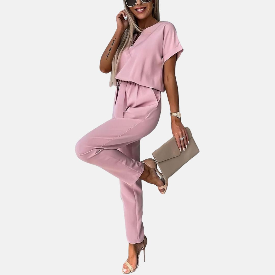 Frau in rosa Jumpsuit mit Sonnenbrille und Clutch, modisches Outfit, elegante Sandalen, lässiger Look, Sommermode, stilvolle Damenbekleidung.
