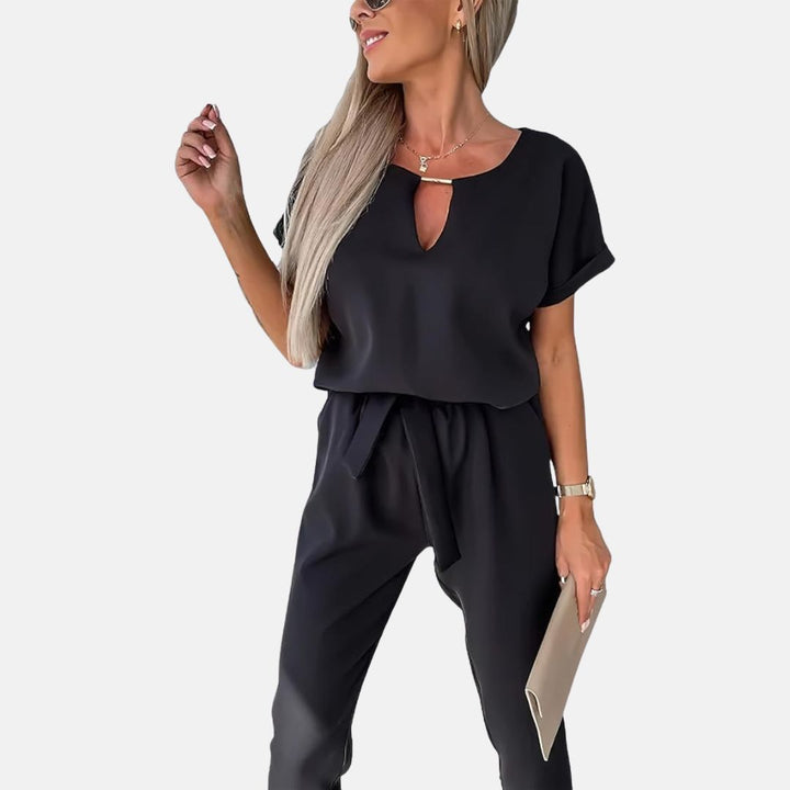 Frau in schwarzem Jumpsuit mit V-Ausschnitt, hält ein Tablet. Elegante Damenmode, modernes Design, Business-Look. Ideal für Büro oder Freizeit.