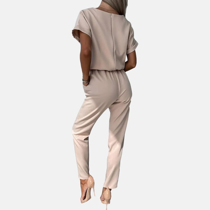 Damen Jumpsuit in Beige, elegantes Design, kurze Ärmel, schmaler Schnitt, ideal für Büro oder Freizeit, kombiniert mit hohen Absätzen.