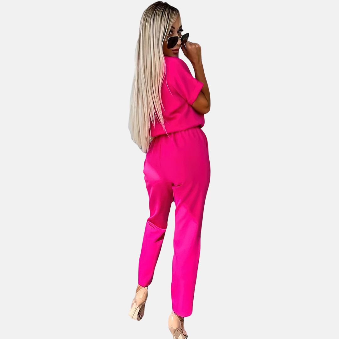 Frau in pinkem Jumpsuit mit langen blonden Haaren und Sonnenbrille, Rückansicht. Modetrend, stilvolle Damenbekleidung, Sommeroutfit.