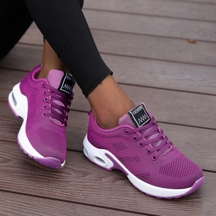 Lila Damen-Sneaker auf Holzterrasse, sportlich und modern, mit atmungsaktivem Mesh-Obermaterial und weißer Sohle. Ideal für Freizeit und Sport.