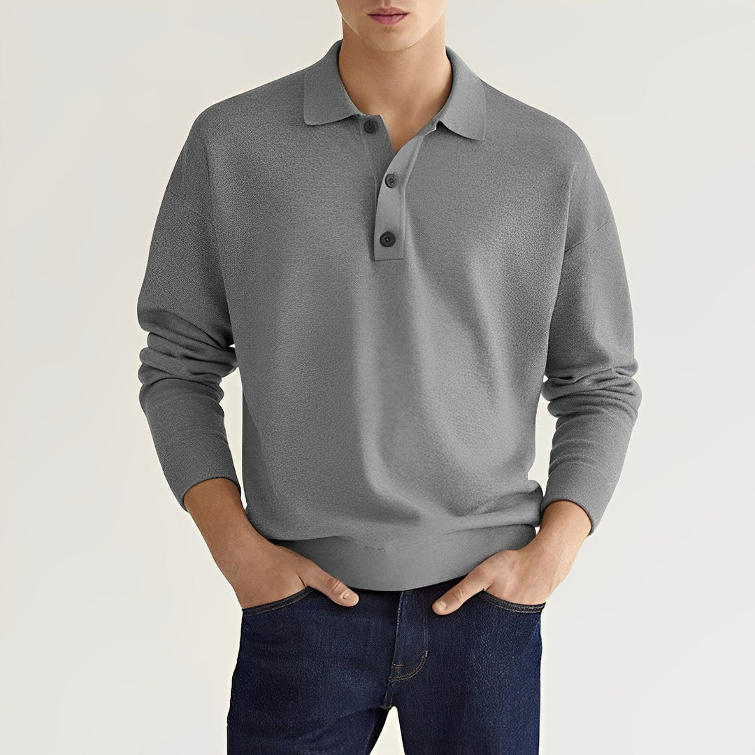 Grauer Herrenpullover mit Kragen und Knopfleiste, kombiniert mit dunkelblauer Jeans. Modischer Freizeitlook für Männer.