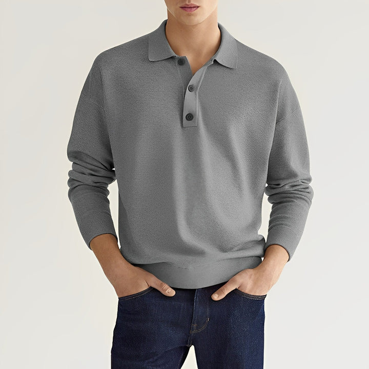 Grauer Herrenpullover mit Kragen und Knopfleiste, kombiniert mit dunkelblauer Jeans. Modischer Freizeitlook für Männer.