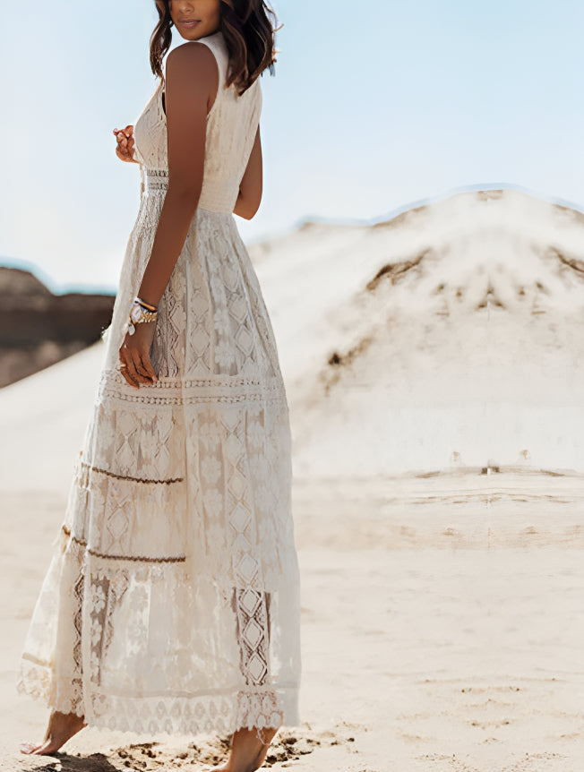 Frau in weißem Spitzenkleid steht in Wüste, Sommermode, Boho-Stil, elegantes Maxikleid, sandige Landschaft, modisches Outfit, Outdoor-Fotoshooting.