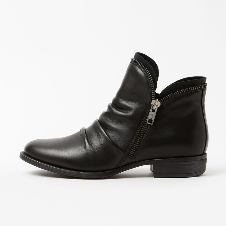 Schwarzer Lederstiefel mit seitlichem Reißverschluss, flachem Absatz und gerafftem Design. Eleganter Damenstiefel, ideal für Herbstmode.