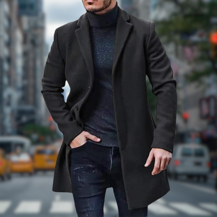 Ein Mann in einem eleganten schwarzen Mantel und Rollkragenpullover geht auf einer belebten Stadtstraße. Hintergrund mit unscharfen Taxis und Gebäuden.