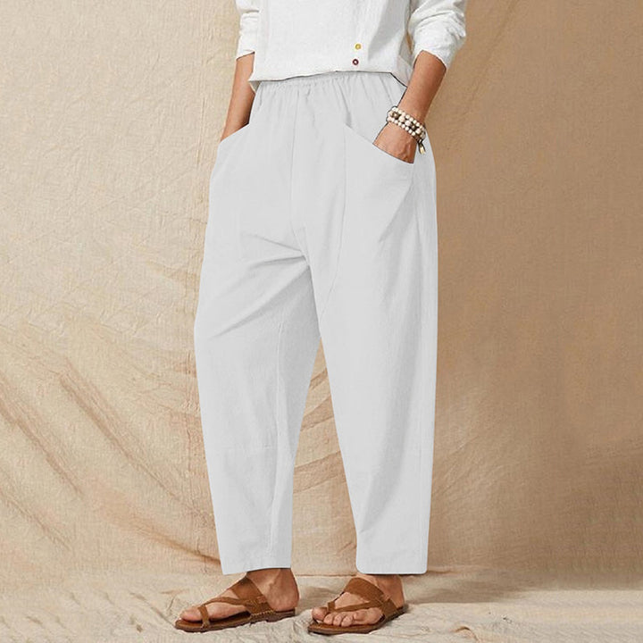 Weiße Damenhose mit elastischem Bund und Taschen, kombiniert mit weißem Oberteil und Sandalen. Bequeme, lässige Mode für den Alltag.