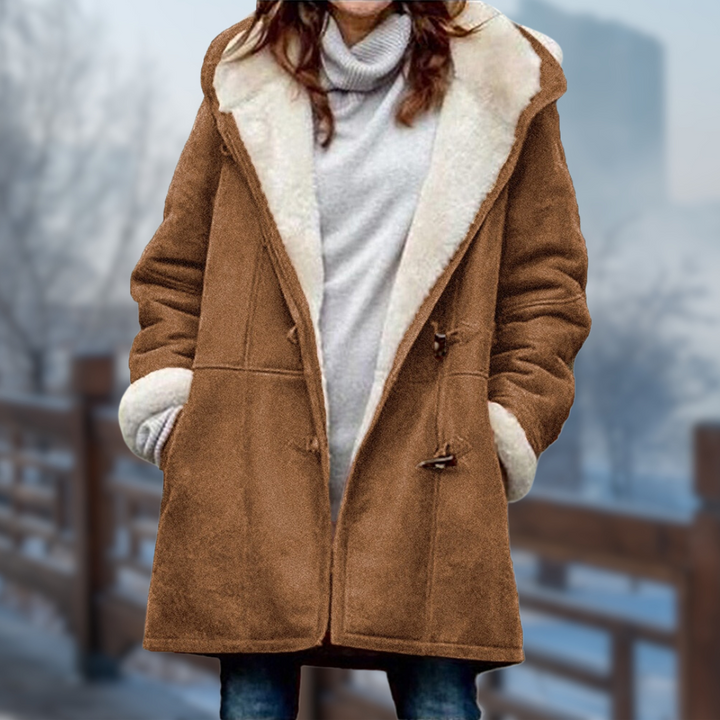 Frau in braunem Wintermantel mit Kapuze und weißem Futter, steht auf einer Brücke im Winter. Modischer Damenmantel, Wintermode, warme Kleidung.