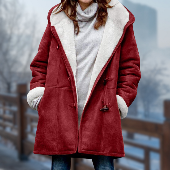 Frau in rotem Wintermantel mit weißem Futter, stehend auf einer verschneiten Brücke. Modischer Damenmantel, Wintermode, warme Bekleidung.