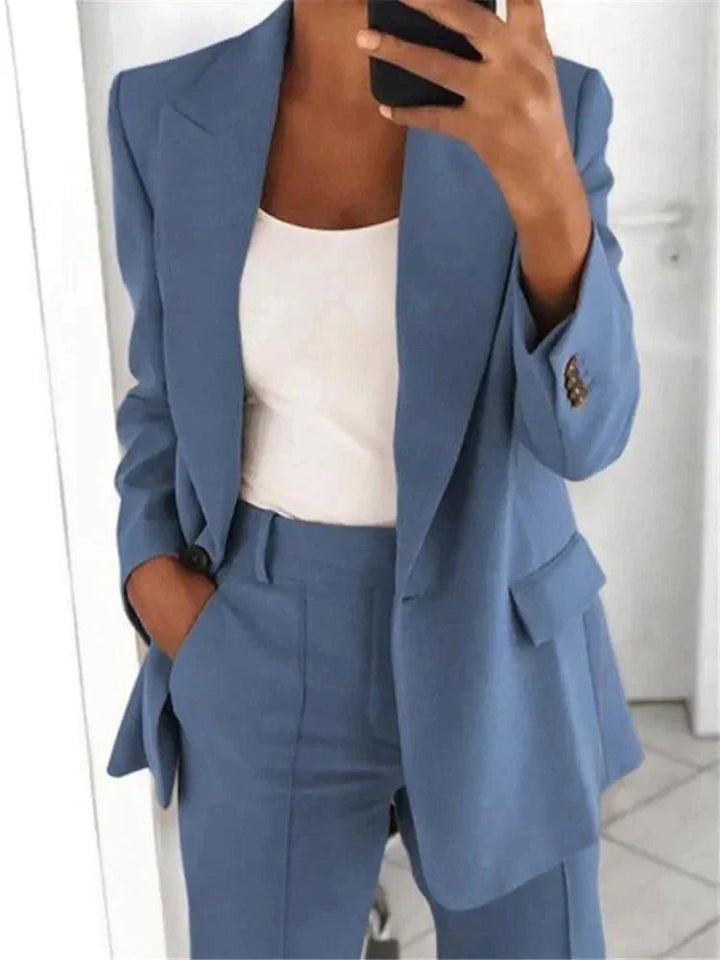 Frau in blauem Anzug mit weißem Top, hält Smartphone. Eleganter Business-Look, moderne Damenmode, Büro-Outfit, stilvolle Kleidung.