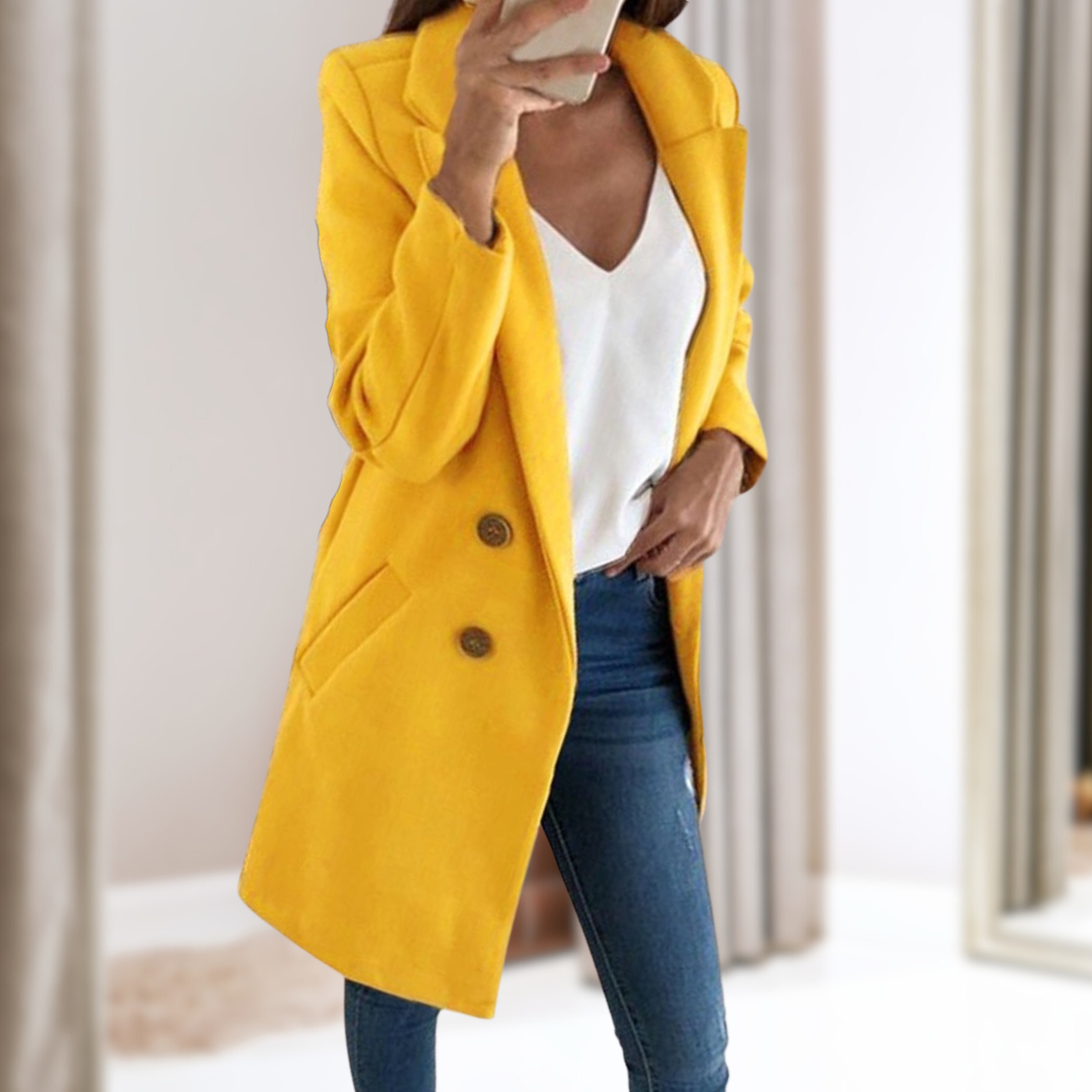Frau in gelbem Mantel, weißem Top und blauer Jeans macht Selfie. Modetrend Herbst, stilvolle Damenbekleidung, eleganter Look.
