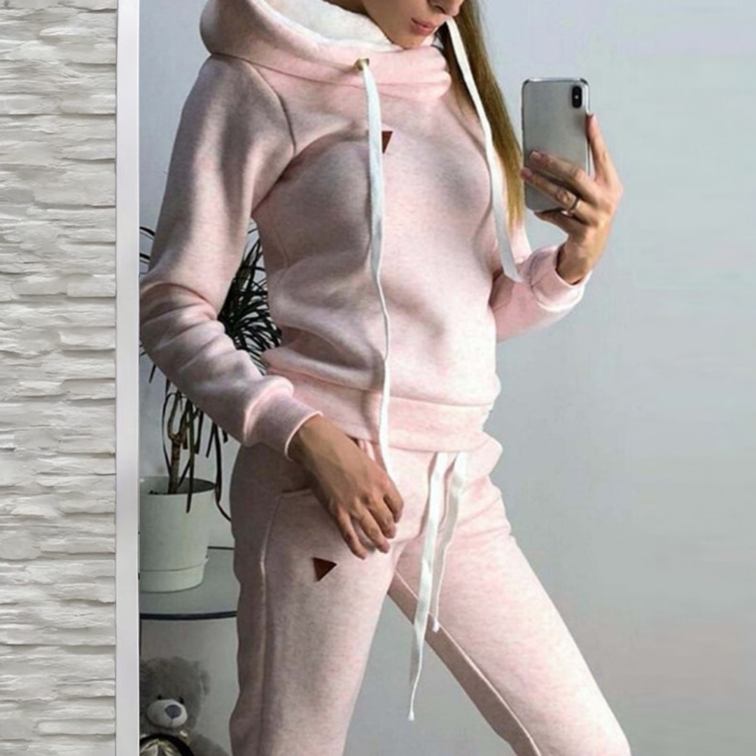 Frau in rosa Jogginganzug macht Selfie, moderner Freizeitlook, gemütlicher Hoodie und Jogginghose, modische Damenbekleidung, Indoor-Fitness-Outfit.