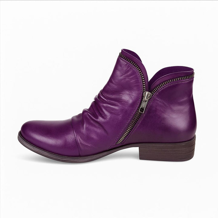 Lila Damenstiefelette aus Leder mit seitlichem Reißverschluss, flachem Absatz und gerafftem Design. Modische Herbstschuhe, bequem und stilvoll.