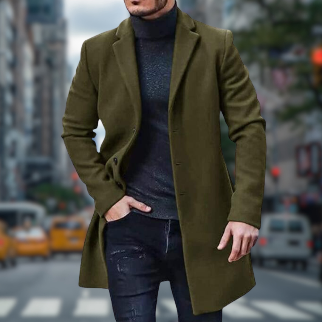 Mann in olivgrünem Mantel und schwarzem Rollkragenpullover auf belebter Stadtstraße mit gelben Taxis im Hintergrund. Elegante Herrenmode.
