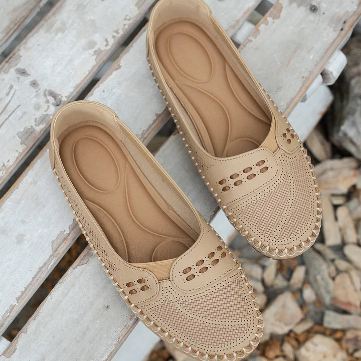 Beige Damen-Loafer aus Leder mit Lochmuster auf Holzbank. Bequeme, stilvolle Schuhe für Alltag und Freizeit. Perfekt für Frühling und Sommer.