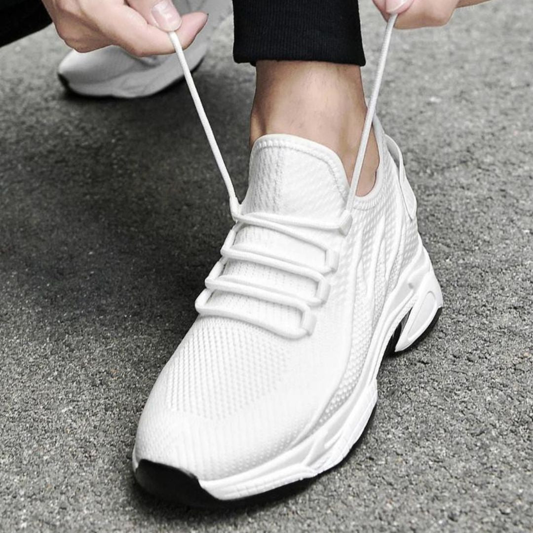 Weiße Sportschuhe mit Schnürsenkeln auf grauem Boden, moderne Sneaker, atmungsaktives Mesh-Design, ideal für Laufen und Fitness.