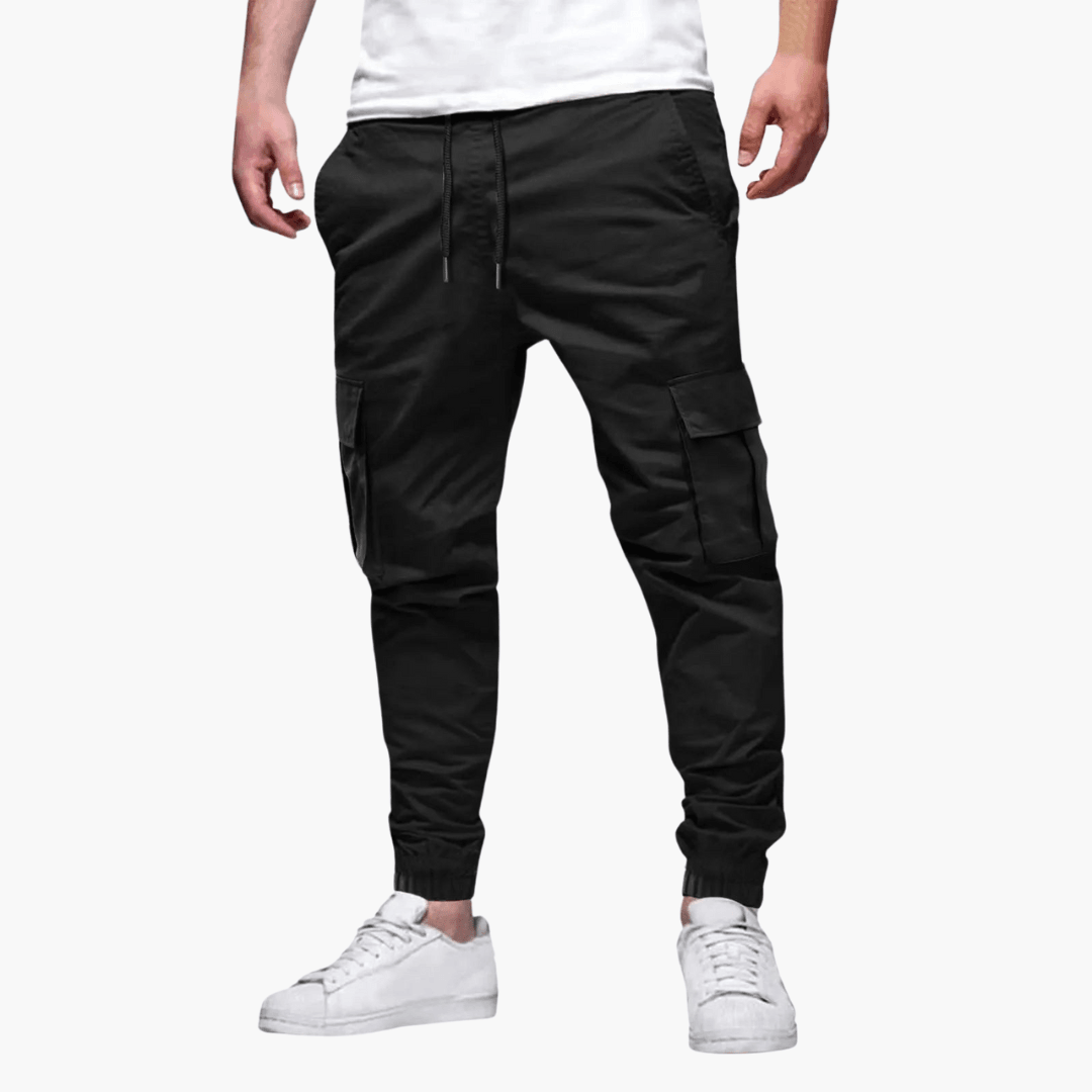 Schwarze Cargo-Jogginghose für Herren, lässiger Stil, mit Seitentaschen, kombiniert mit weißen Sneakers. Ideal für Freizeit und Streetwear.