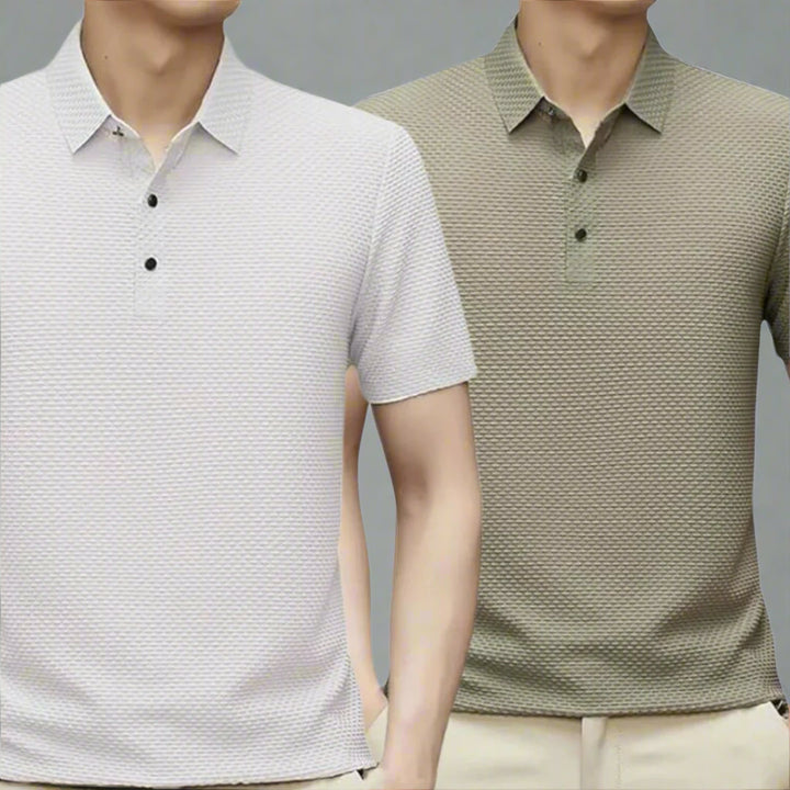 Zwei Männer in strukturierten Poloshirts, eines in Weiß, das andere in Olivgrün, vor grauem Hintergrund. Mode, Herrenbekleidung, Poloshirts.