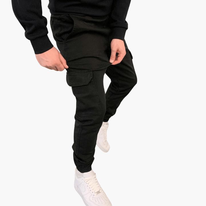 Schwarze Cargo-Hose für Herren, kombiniert mit weißen Sneakers und schwarzem Pullover. Modische Herrenbekleidung, lässiger Streetwear-Stil.