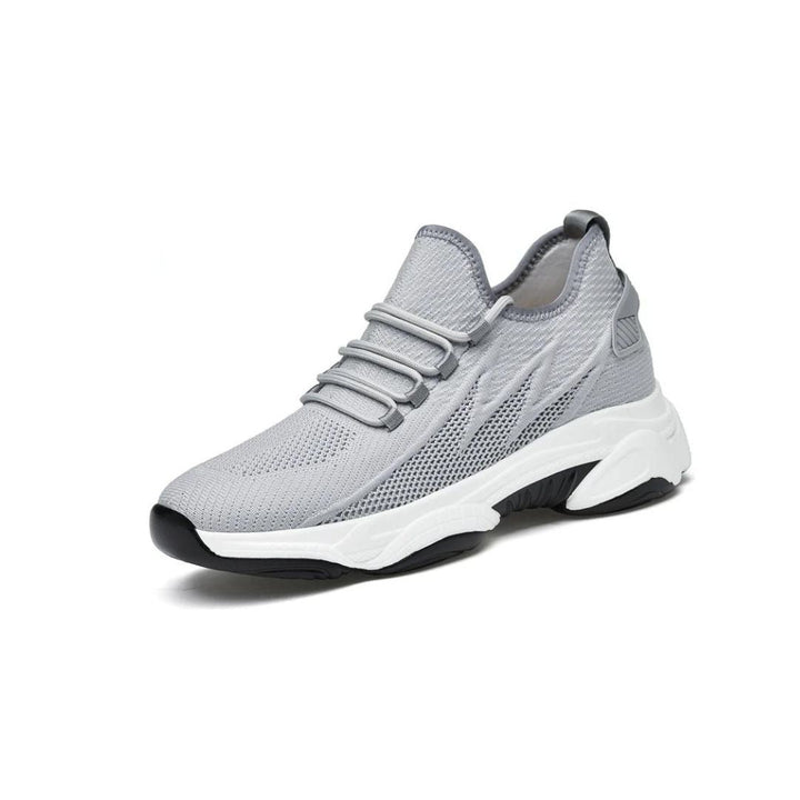 Grauer Sneaker mit atmungsaktivem Mesh-Obermaterial, weißer Sohle und schwarzem Akzent. Modischer Sportschuh für Herren, ideal für Laufen und Freizeit.