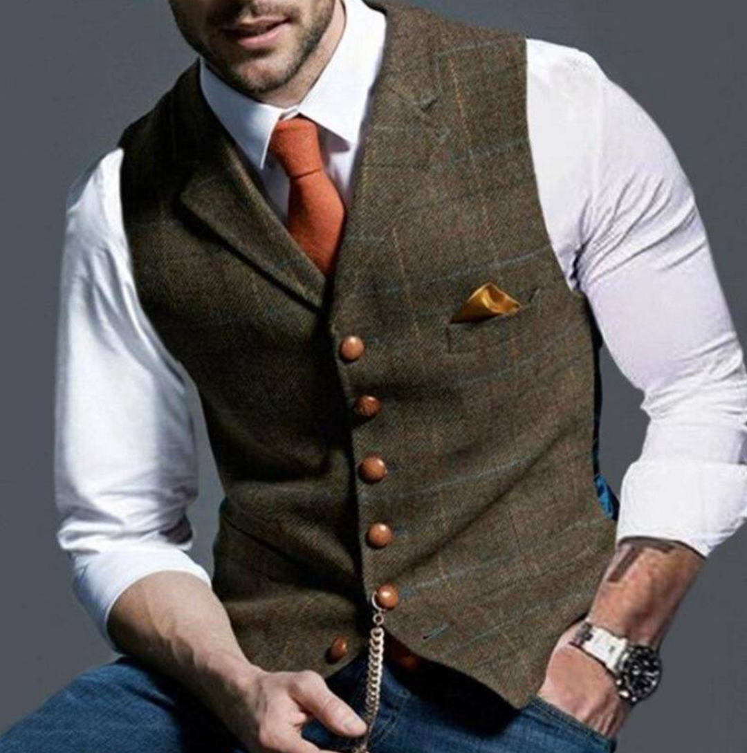 Mann in eleganter brauner Weste mit orangefarbener Krawatte und Einstecktuch, weißem Hemd und Armbanduhr. Stilvolle Herrenmode, Business-Look.