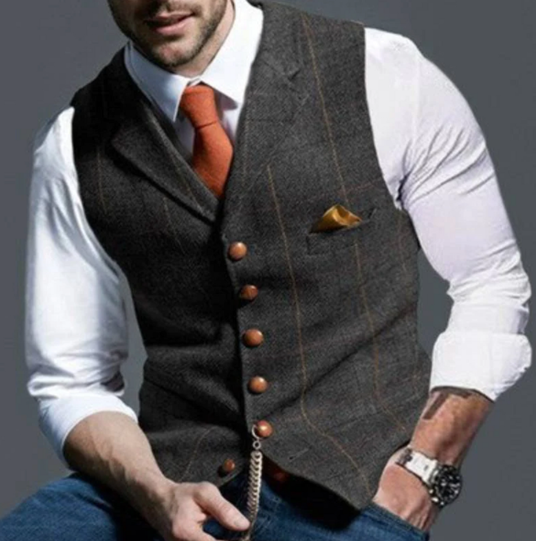 Mann in eleganter grauer Weste mit orangefarbener Krawatte und Einstecktuch, weißem Hemd und Armbanduhr. Businessmode, Herrenbekleidung, stilvoll.