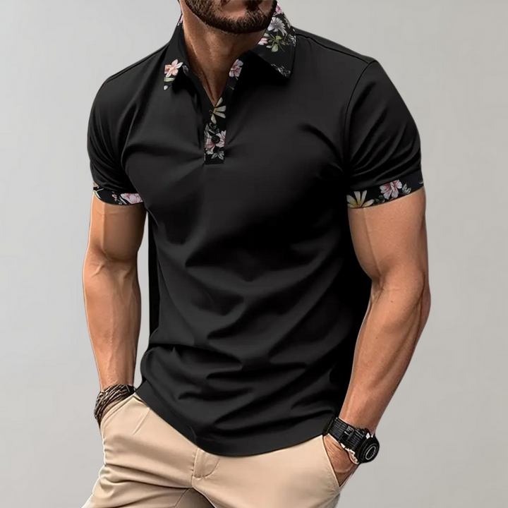 Mann in schwarzem Polohemd mit Blumenmuster an Kragen und Ärmeln, beige Hose, Armbanduhr. Elegante Herrenmode, stilvolles Freizeitoutfit.