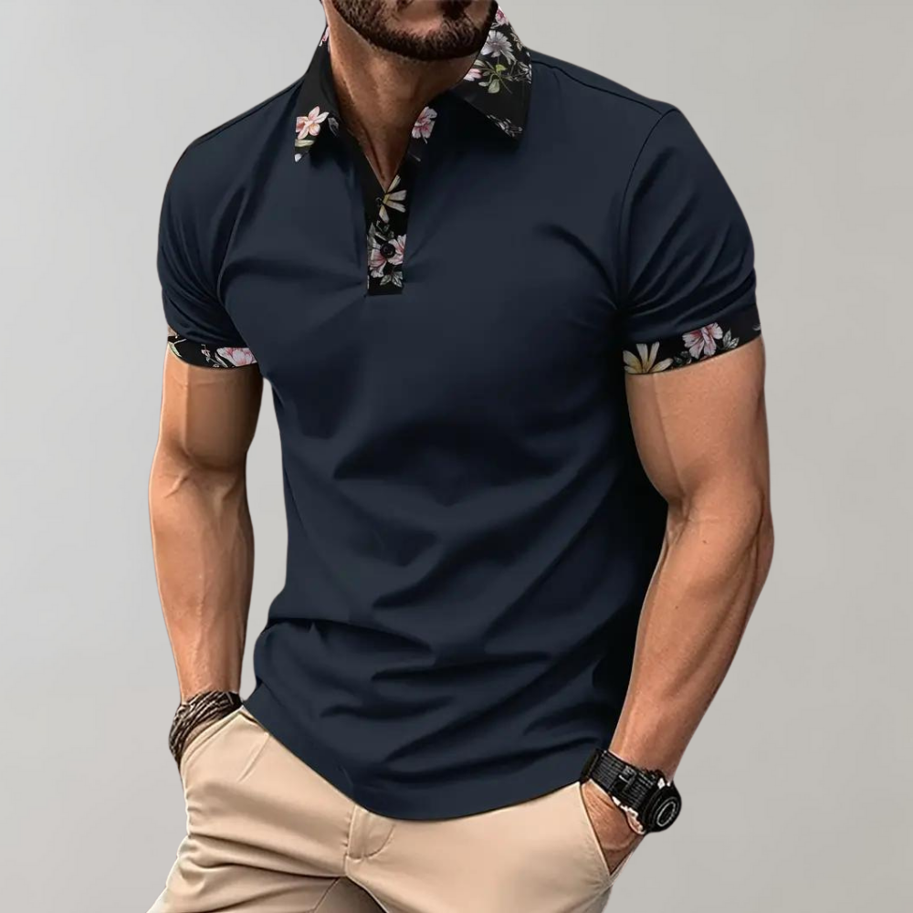 Dunkelblaues Herren-Poloshirt mit floralen Akzenten an Kragen und Ärmeln, kombiniert mit beigen Hosen. Modischer Freizeitlook für Männer.