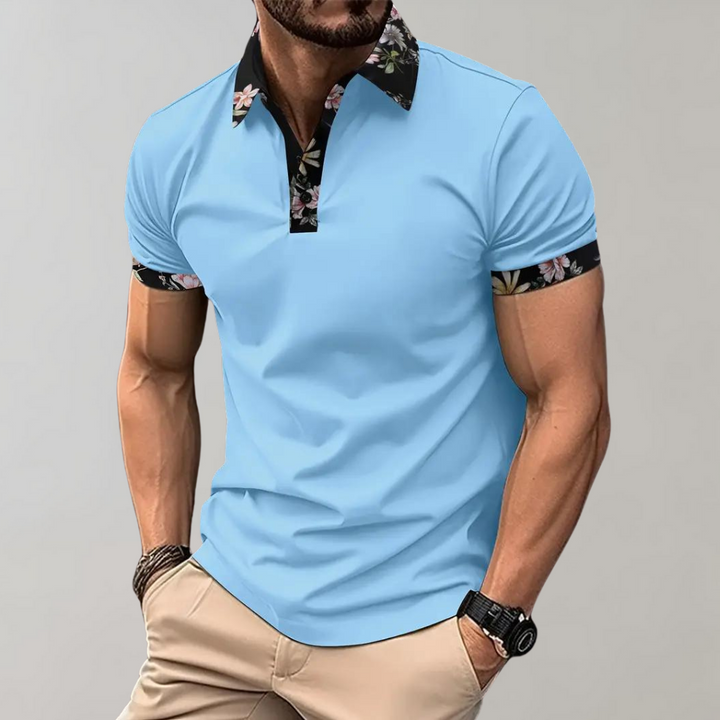 Herren T-Shirt in Hellblau mit floralen Akzenten am Kragen und Ärmeln, kombiniert mit beigen Hosen. Modisches Männeroutfit, Sommermode.