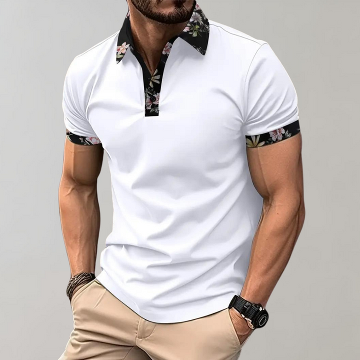 Herren-Poloshirt in Weiß mit floralen Akzenten an Kragen und Ärmeln, kombiniert mit beigen Hosen. Modischer Freizeitlook für Männer.